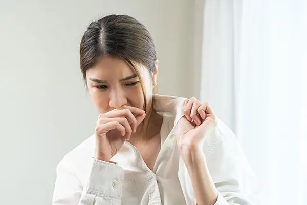 Woman smelling musty odor before cockroach control in Charlotte, NC by Cardinal Environmental Solutions